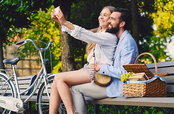 happy couple taking a selfie in a park